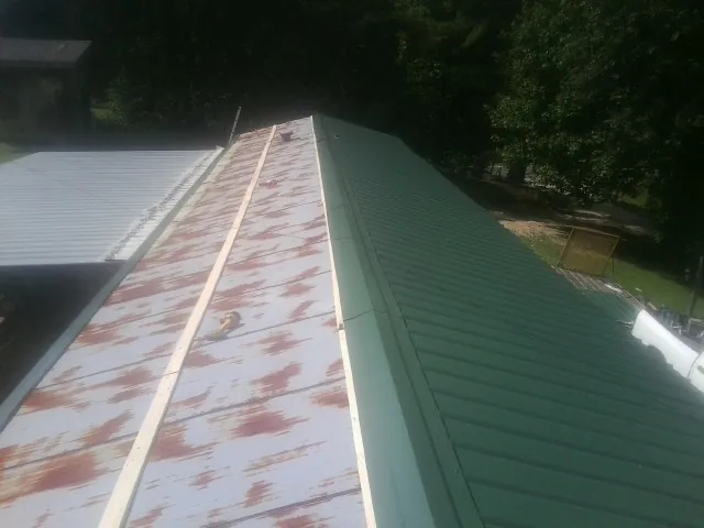 Old rusted panels beside newly installed green metal roofing — Wind Damage Roof Repair by Roofing Brothers in Sylvania