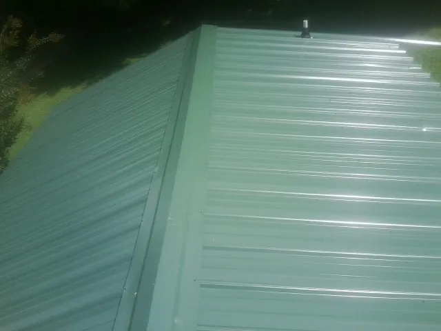 New green metal panels meeting at the ridge of a roof — Flat Roof Repair work by our crew in Sylvania