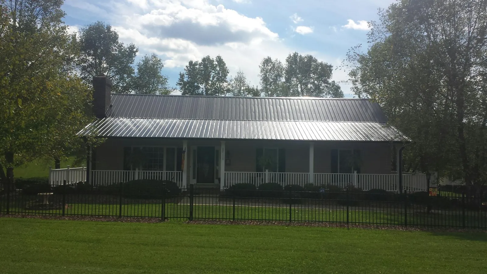Gray metal roof on a brick ranch with a full width front porch — Gutter Guard Installation work by our crew in Sylvania