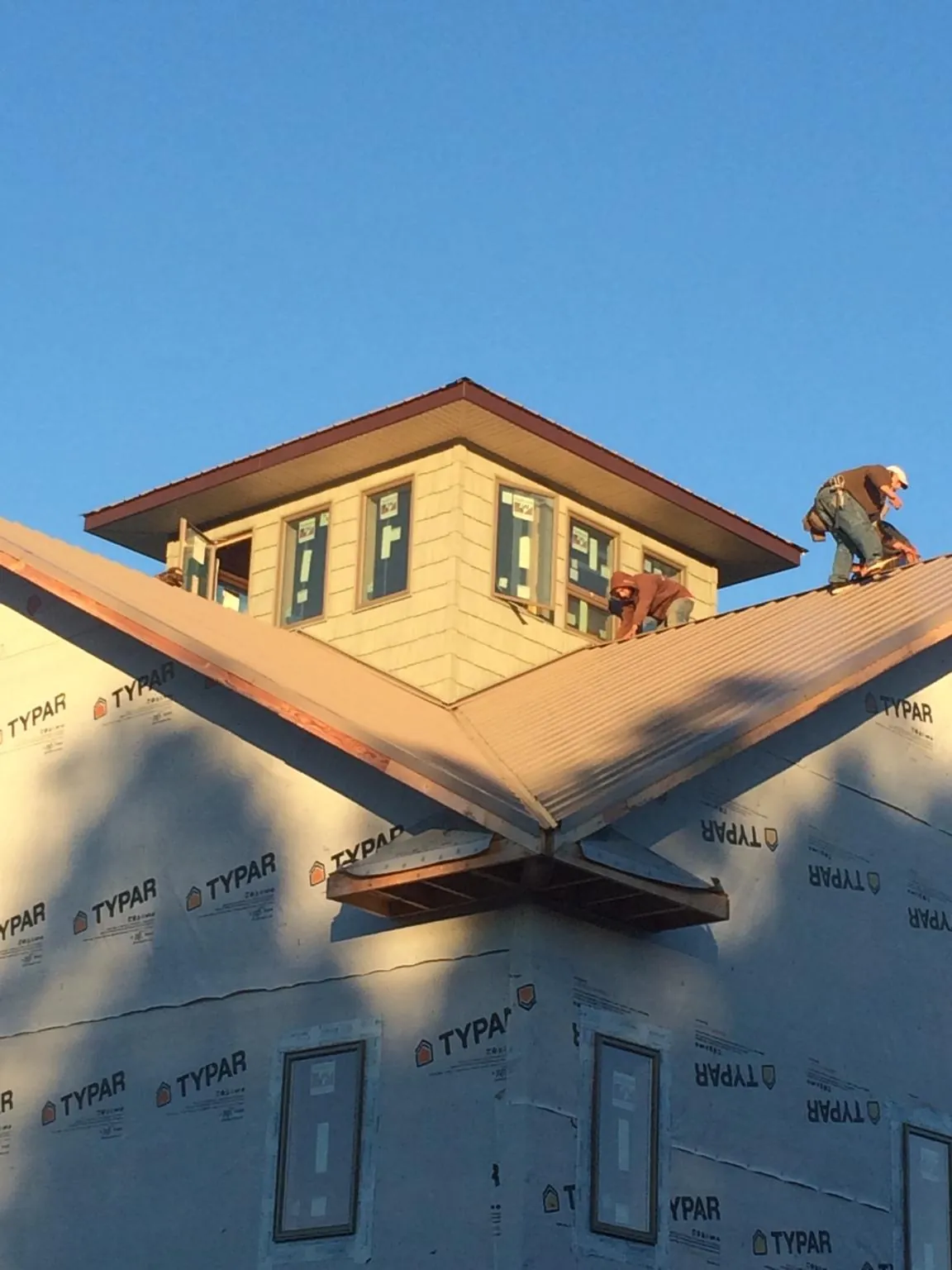 Roofers working around a rooftop cupola on a new metal roof at sunset — Roof Waterproofing in Sylvania by Roofing Brothers